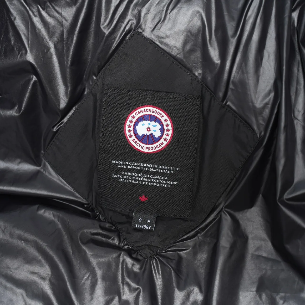 P940 Canada Goose Lawrence Down Jacket The Lawrence Down Jacket provides essential protection for everyday adventures and is made from sustainable Enduraluxe fabric with a durable soft touch. It features a quilted body, an adjustable down hood and a longer hem. Adjustable, down-filled, communicated hood. Two-way center front zipper increases range of motion and ventilation. The chin-protecting suede knit stand-up collar is soft and extra-comfortable. Inset rib-knit cuffs for added comfort and locked in heat. CORDURAD piping at the cuffs hem and reflective double-stripe grip tape at the back. Internal shoulder strap Color: black with red label black with black label azure blue Size: XS-2XL